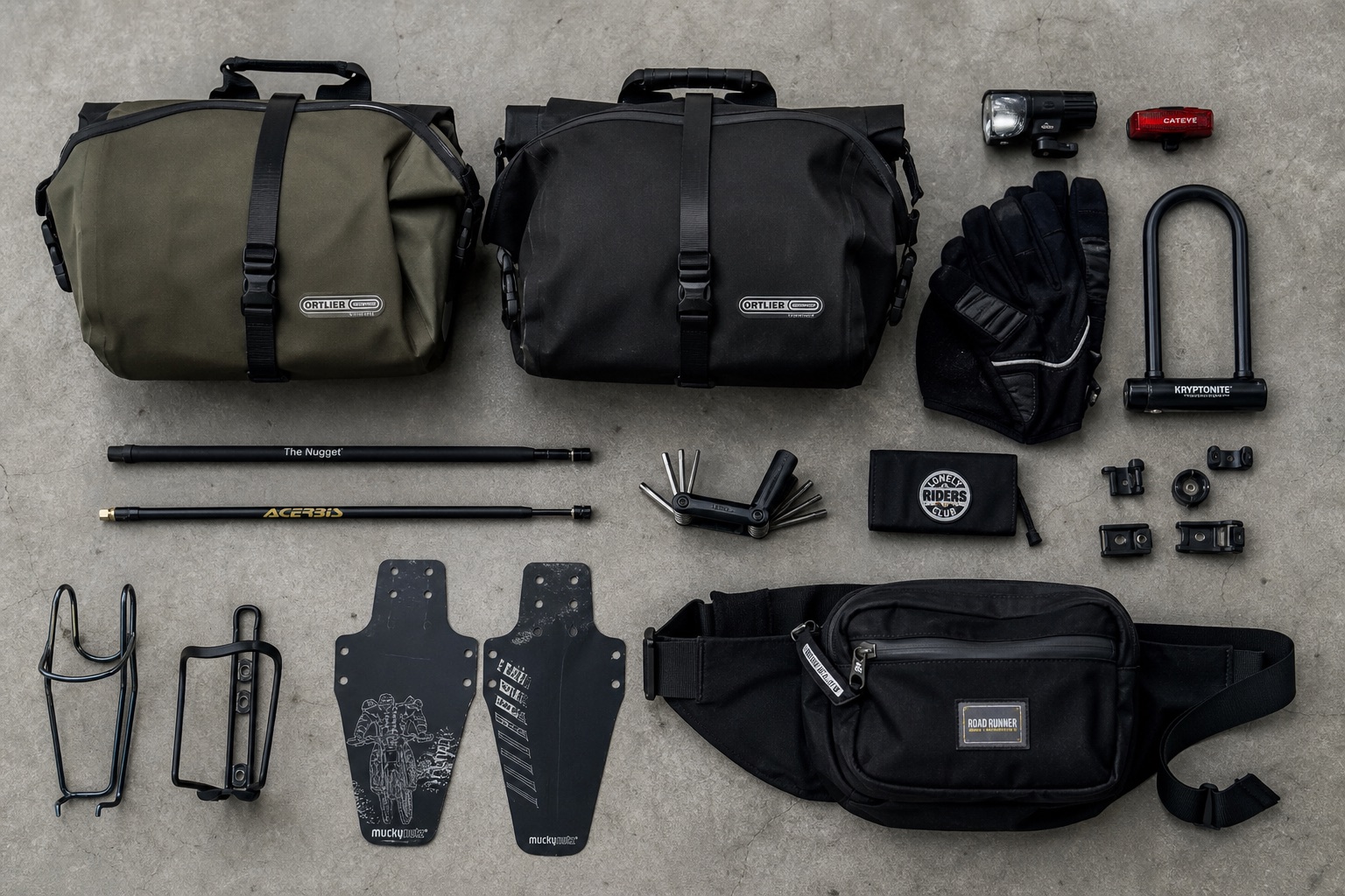 Flat-lay of commuting gear on raw concrete: panniers, lights, fenders, gloves and a lock
